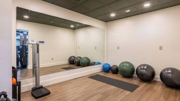 A gym with exercise equipment, a mirror, and exercise balls.