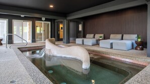 A spa area with a hot tub, seating, and a view of the outside. - The Meadowmere Resort (Ogunquit)