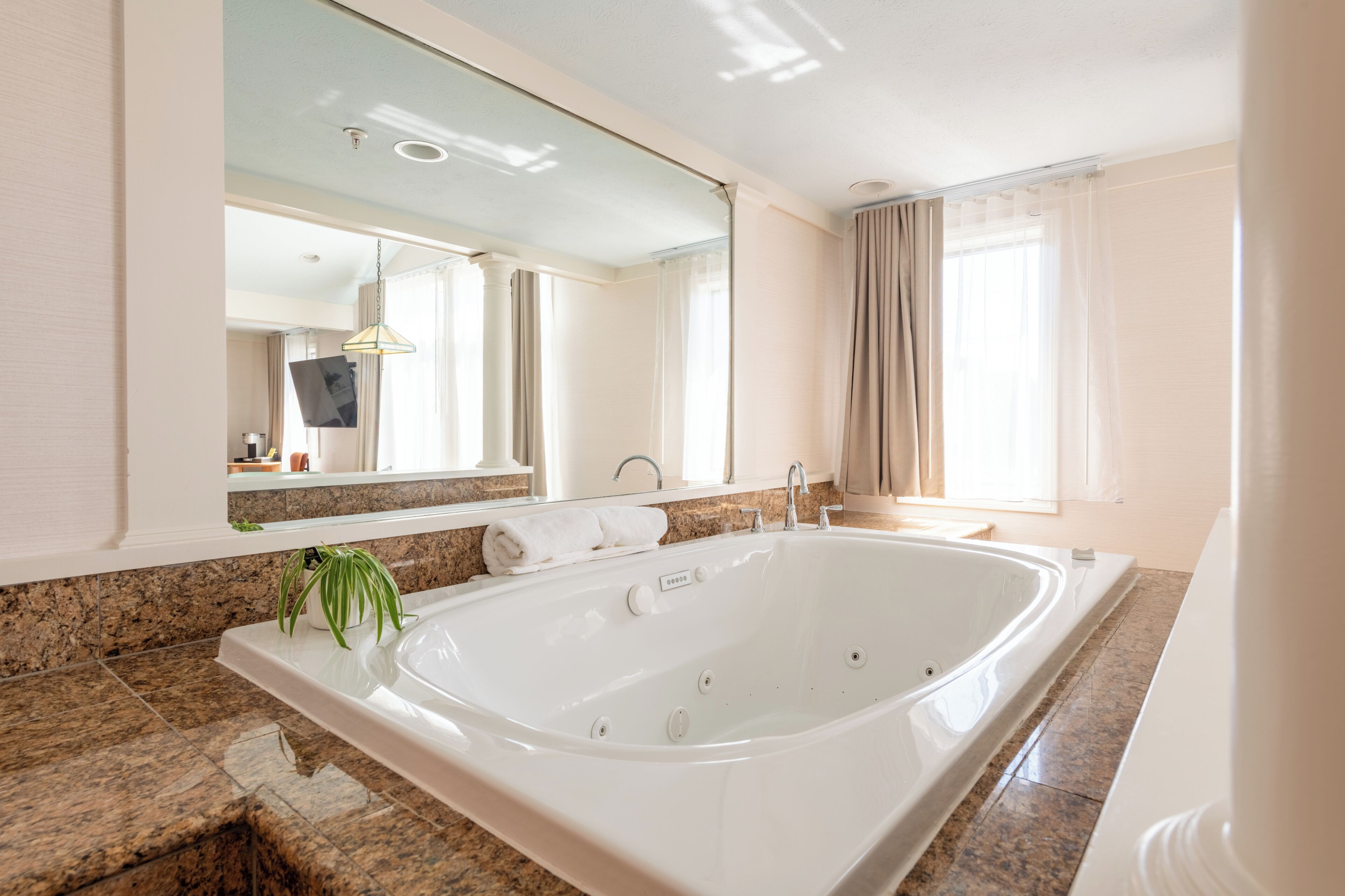 Ein modernes Badezimmer mit einer großen Badewanne, einem Spiegel und einer Arbeitsplatte aus Granit.
