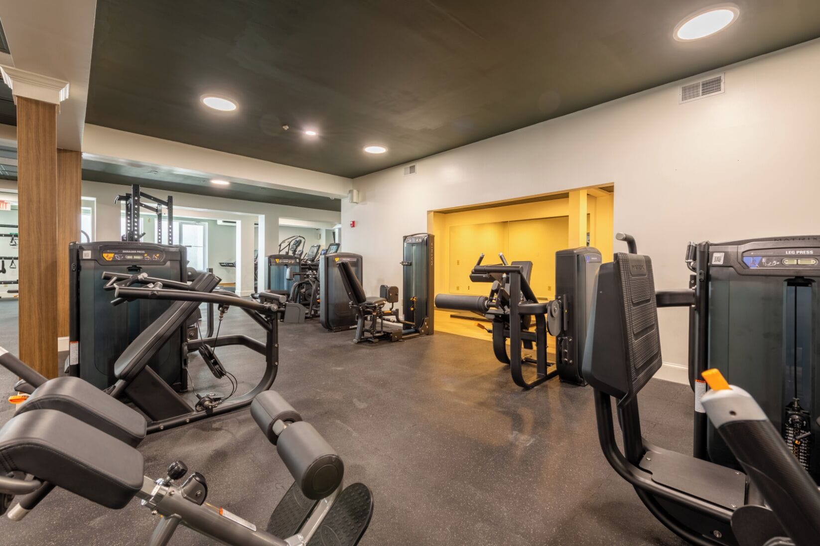 Ein Fitnessraum mit verschiedenen Trainingsgeräten, einer Holzsäule und einem Wandlüfter.