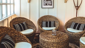 Wicker chairs with white cushions, a cowhide rug, and wall-mounted lamps. - Stables Inn (Paso Robles)