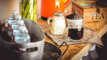 A wooden table with a glass pitcher, a glass cup, and a bottle of milk.
