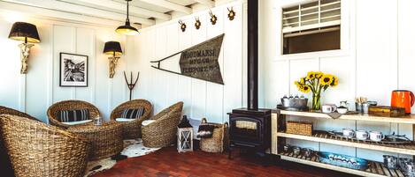 A cozy living room with wicker furniture, a wood-burning stove, and a wall-mounted sign.