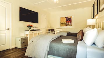 Une chambre à coucher avec un lit, des tables de chevet, une télévision, un tableau et une lampe.