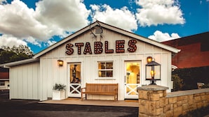 A white building with a sign reading "STABLES" and a wooden bench in front. - Stables Inn (Paso Robles)