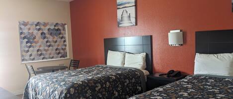 Une chambre d’hôtel avec deux lits, un bureau, une chaise, un téléphone et un tableau au mur.
