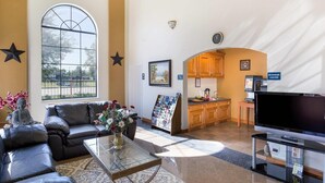 A spacious living area with a large window, a sofa, a coffee table, and a television. - Rodeway Inn & Suites Humble IAH (Humble)