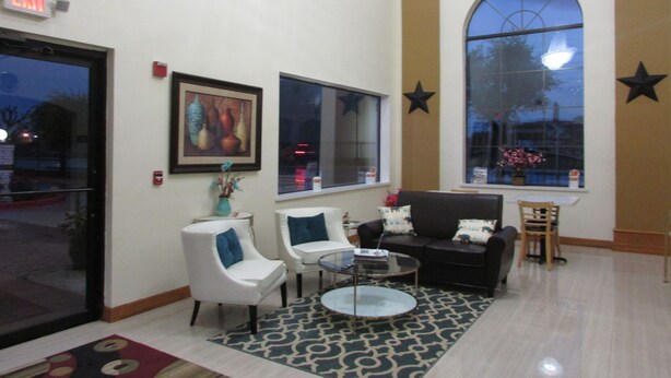 A spacious lobby with a large window, a painting, and a star decoration on the wall. - Rodeway Inn & Suites Humble IAH (Humble)