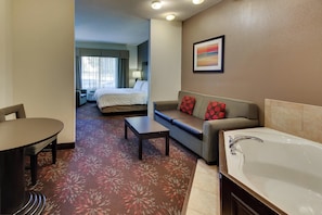 A hotel room with a bed, a sofa, a table, a chair, a bathroom with a bathtub, and a window with curtains. - Holiday Inn Express Hotel & Suites Lancaster-Lititz by IHG (Lititz)