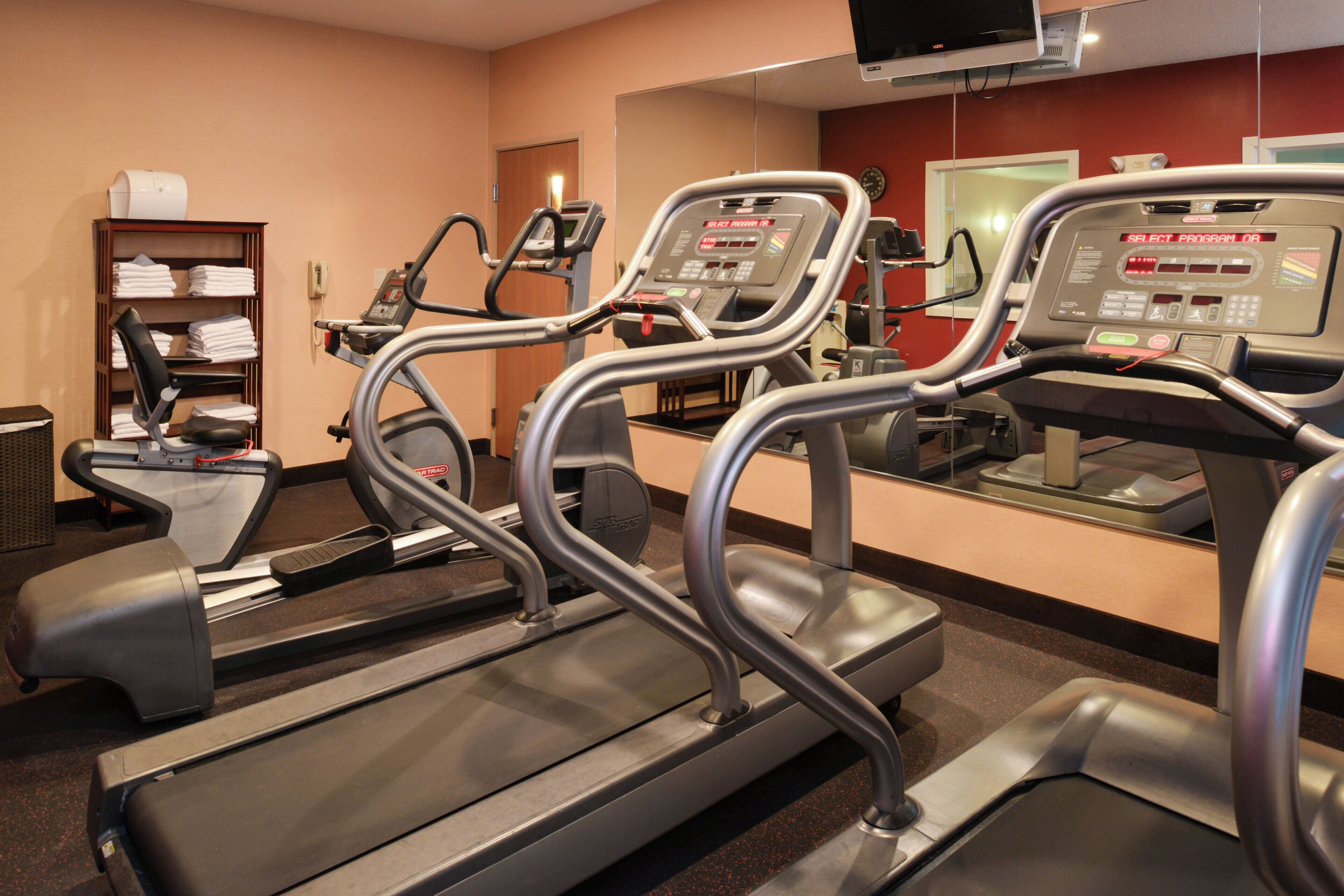 Un gimnasio con cintas de correr, un televisor en la pared y un teléfono.