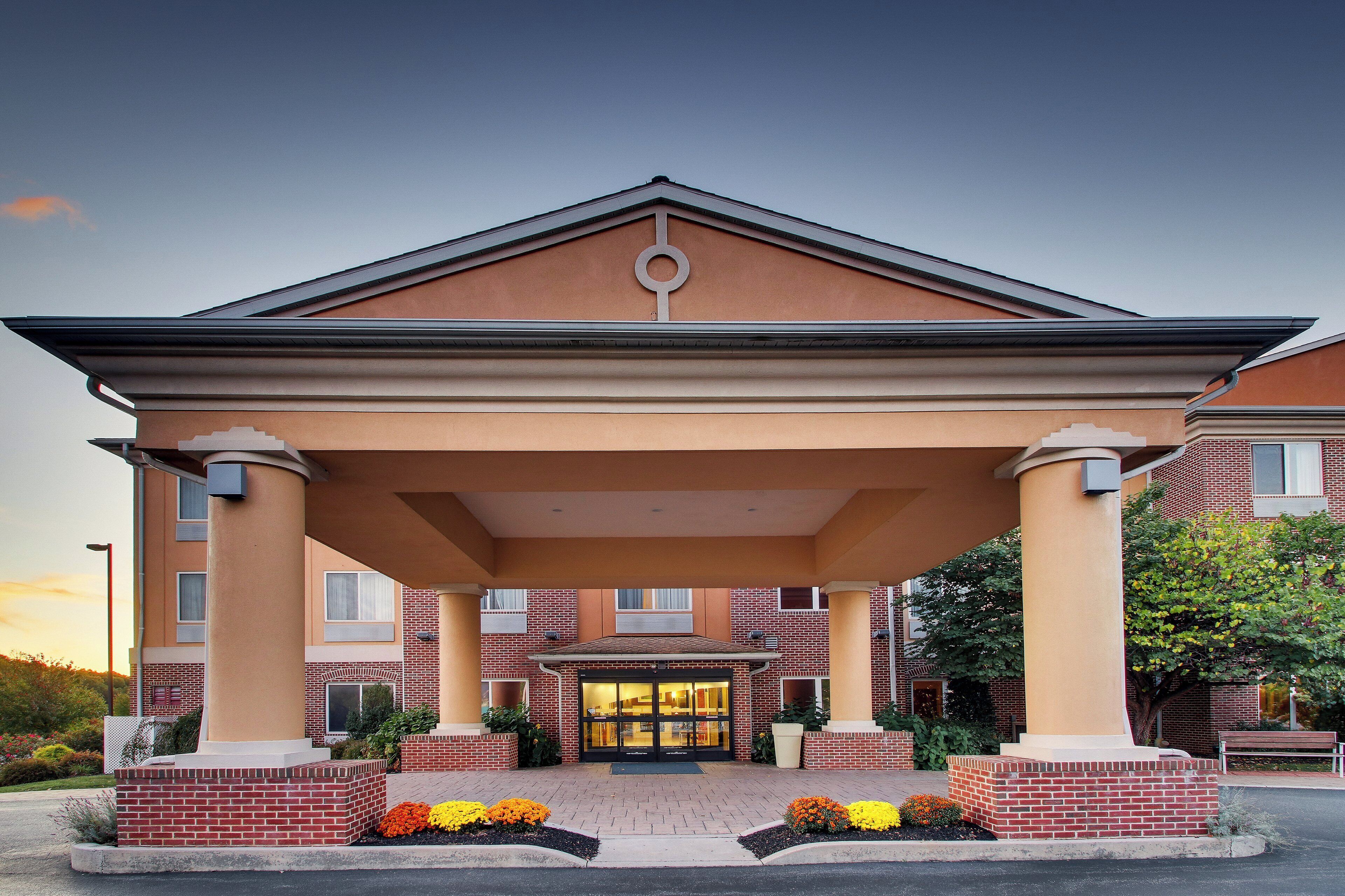 A hotel entrance with a covered patio, brick facade, and a welcoming entrance.