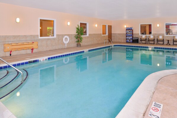 A swimming pool with a tiled edge, a bench, a lifebuoy, and a chair by the poolside.
