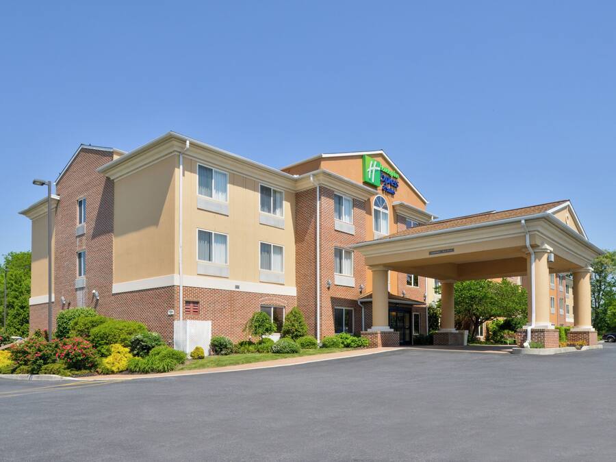 Um hotel Holiday Inn Express com entrada coberta, fachada de tijolos e jardins bem cuidados.