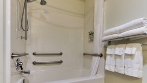 A bathroom with a bathtub, grab bars, a showerhead, and a towel rack with folded towels. - Holiday Inn Express Hotel & Suites Lancaster-Lititz by IHG (Lititz)