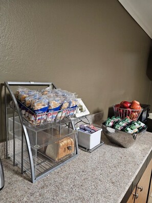 A breakfast bar with packaged food items, a fruit basket, and a container of yogurt. - Super 8 by Wyndham Lake Charles Northeast (Lake Charles)