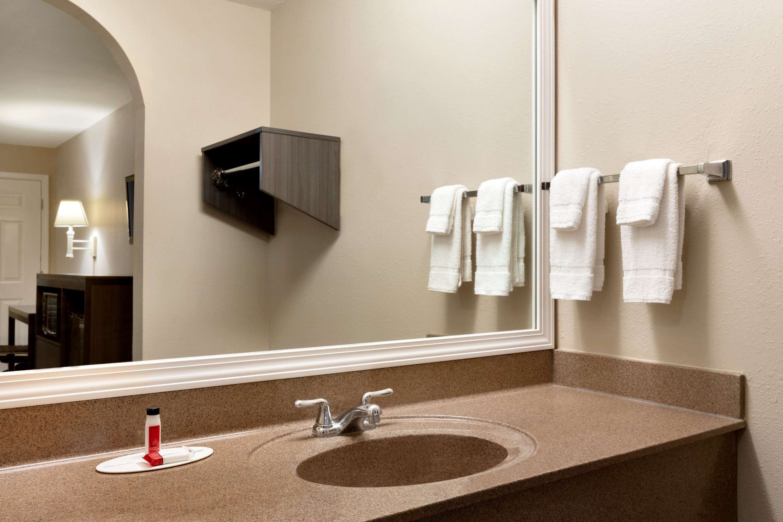 A bathroom with a sink, mirror, towel rack, and a small cabinet.