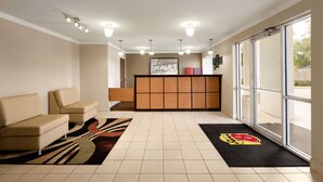 A hotel lobby with a reception desk, a sofa, and a large window. - Super 8 by Wyndham Lake Charles Northeast (Lake Charles)