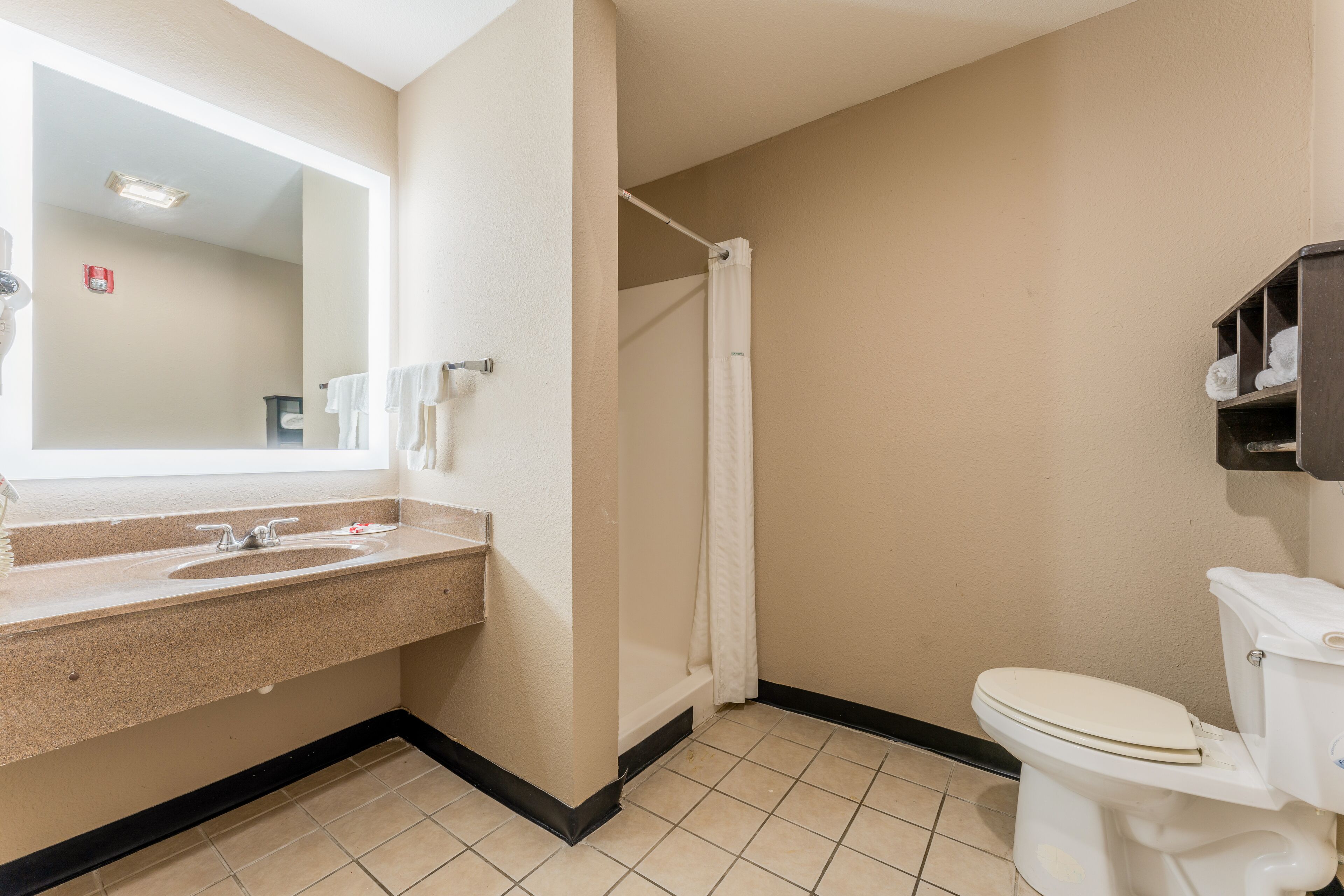 Un bagno con lavandino, specchio, wc e tenda della doccia.