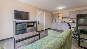 A compact living space with a kitchenette, a flat-screen TV, a refrigerator, a microwave, a toaster, and a dining table. - Super 8 by Wyndham Lake Charles Northeast (Lake Charles)