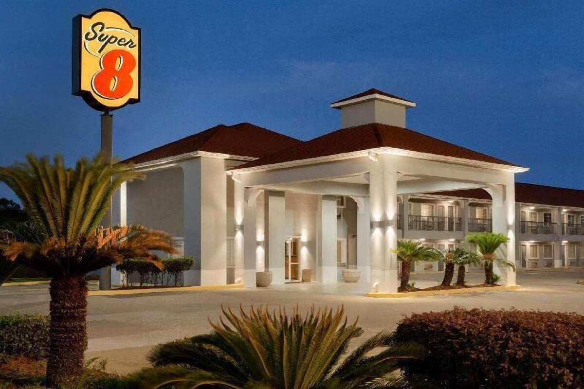 A hotel with a covered entrance, palm trees, and a sign reading 'Super 8'.