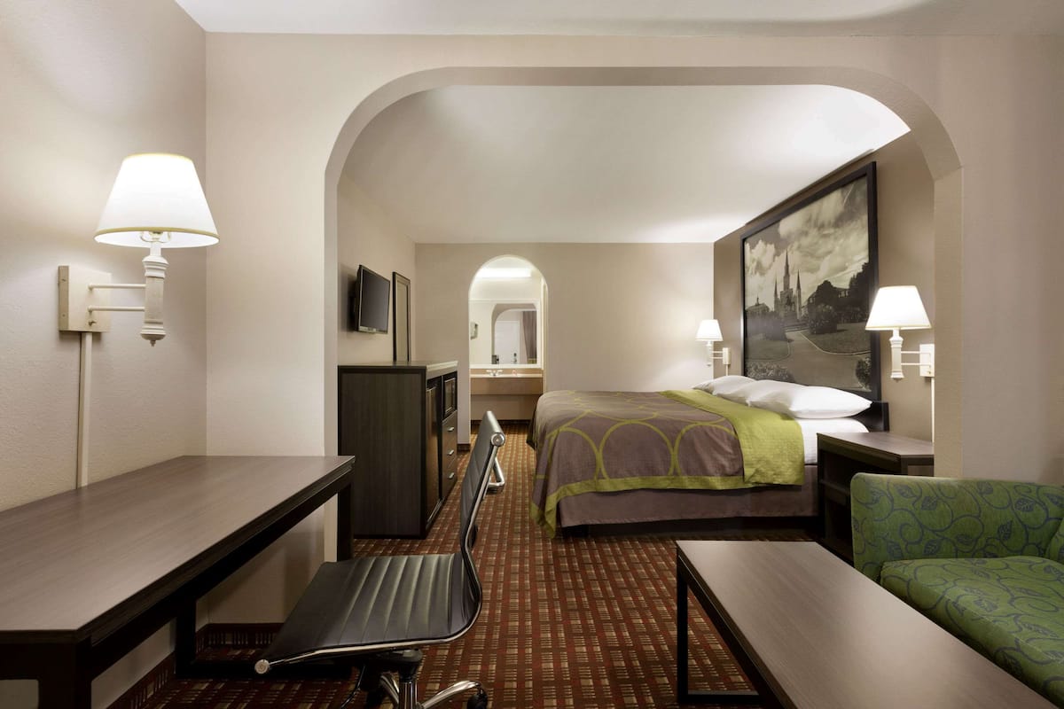 A hotel room with a bed, desk, chair, and a television.