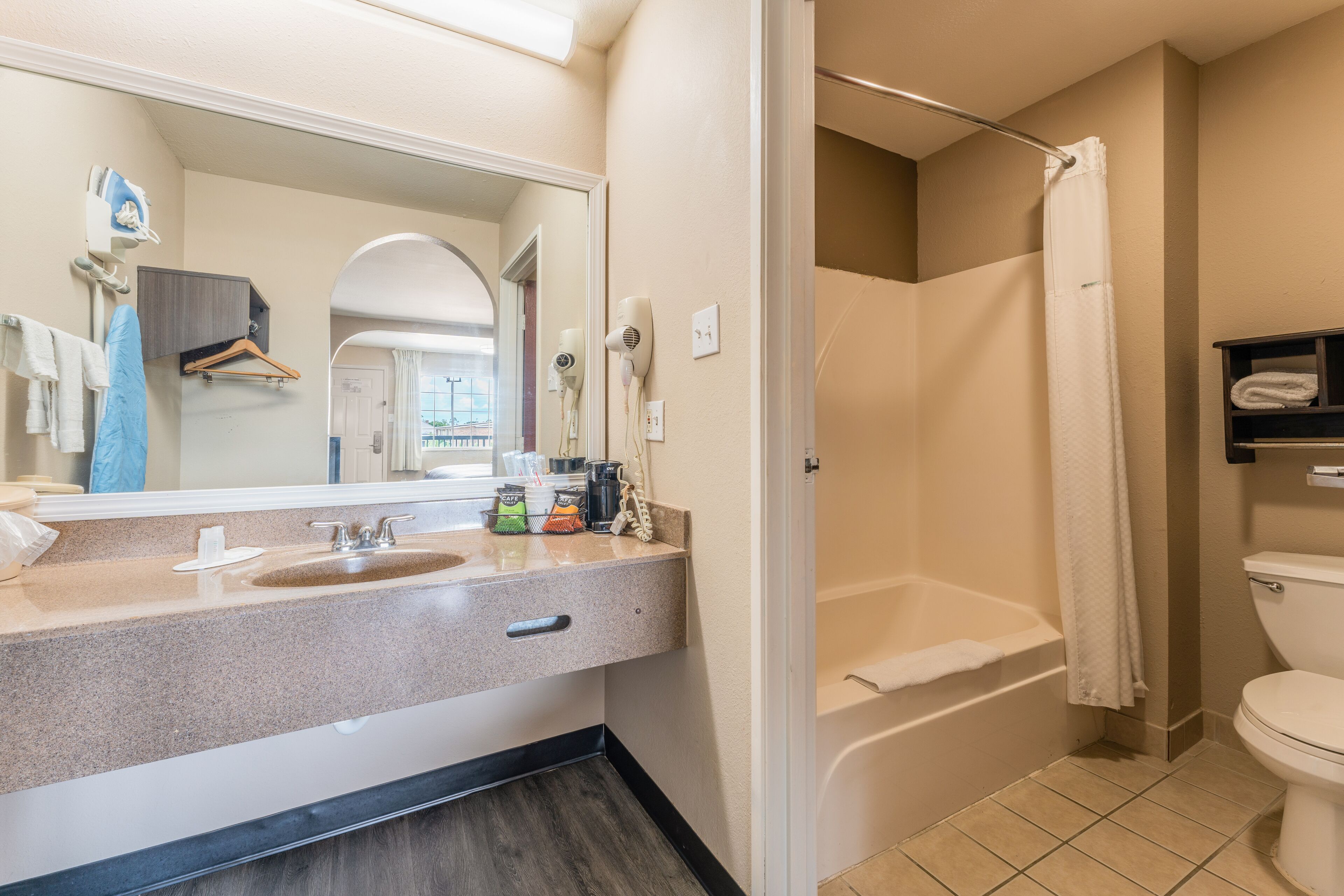 A bathroom with a sink, mirror, towel rack, and a shower area.