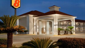 A hotel with a prominent 'Super 8' sign, a covered entrance, and a well-lit facade. - Super 8 by Wyndham Lake Charles Northeast (Lake Charles)