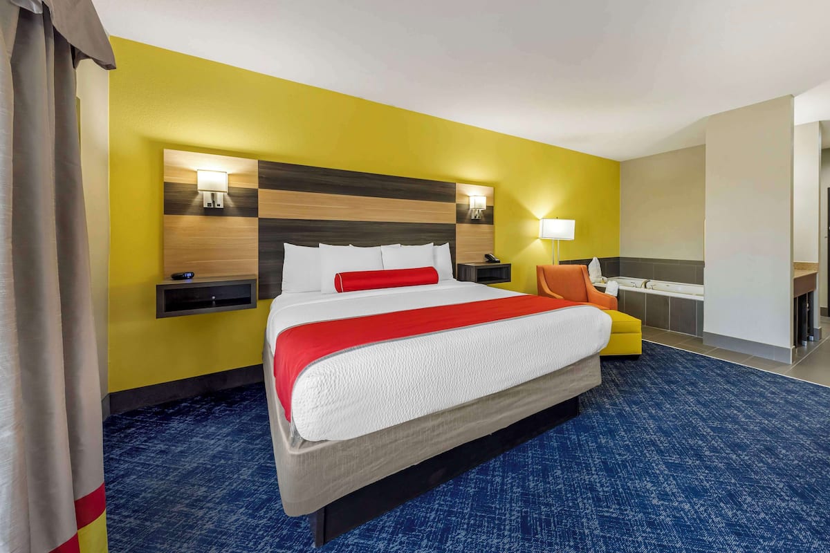 A hotel room with a large bed, a desk, and a bathroom.