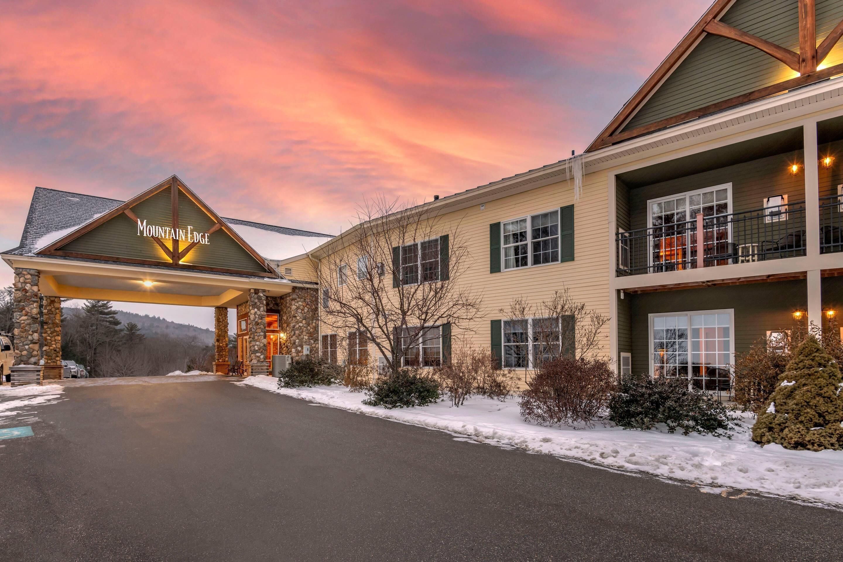 A hotel with a prominent entrance sign, a covered parking area, and a two-story building with balconies.