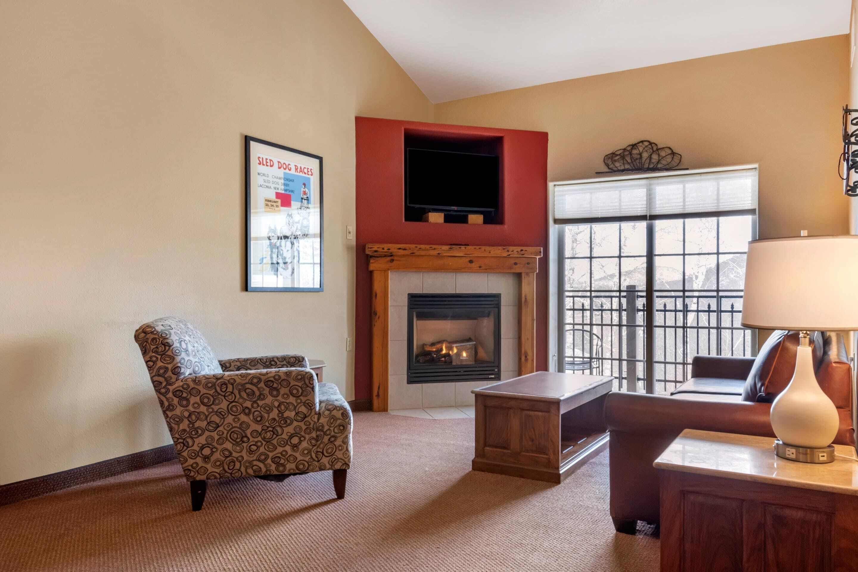 A living room with a fireplace, a sofa, a coffee table, and a TV mounted on a red wall.