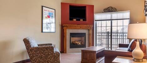 A living room with a fireplace, a sofa, a coffee table, and a TV mounted on a red wall.