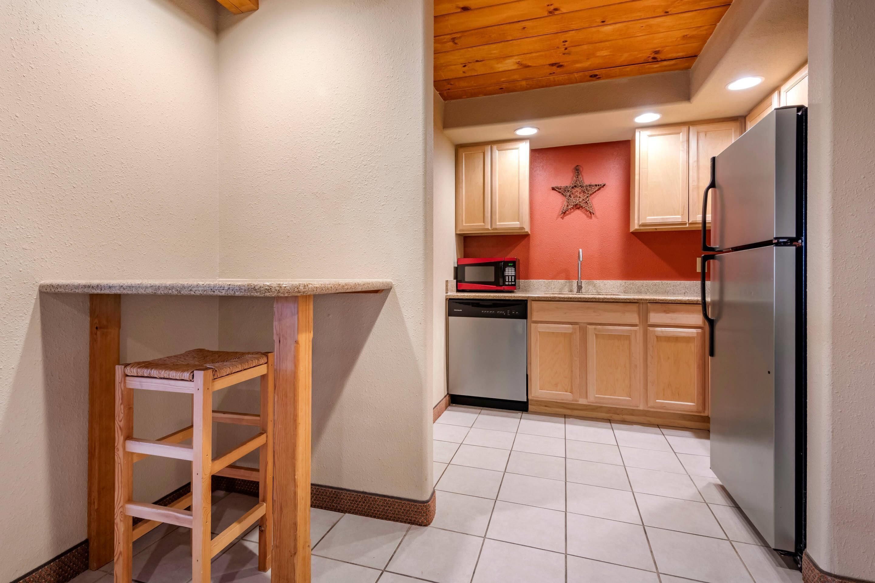 Una cocina con armarios de madera, un refrigerador de acero inoxidable, un microondas y un lavavajillas.