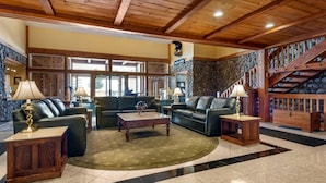 A spacious living room with a fireplace, leather sofas, and a stone accent wall.