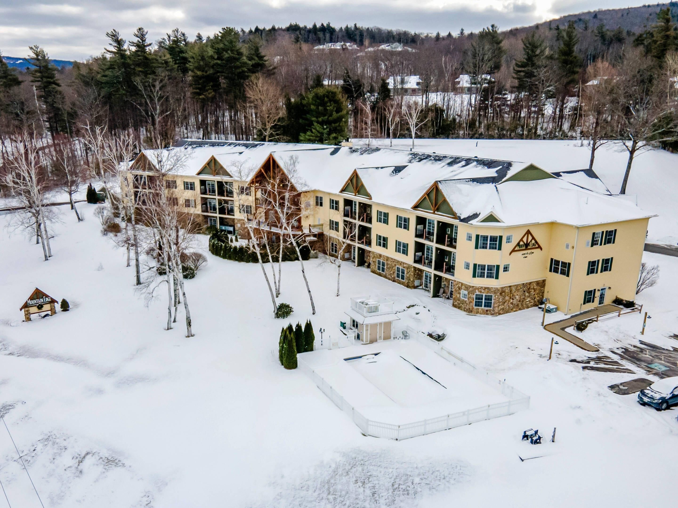 A large, multi-story lodge with a snow-covered roof and a ski lift visible in the background.