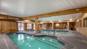 An indoor swimming pool with wooden walls and ceiling, clear water, and multiple lanes.