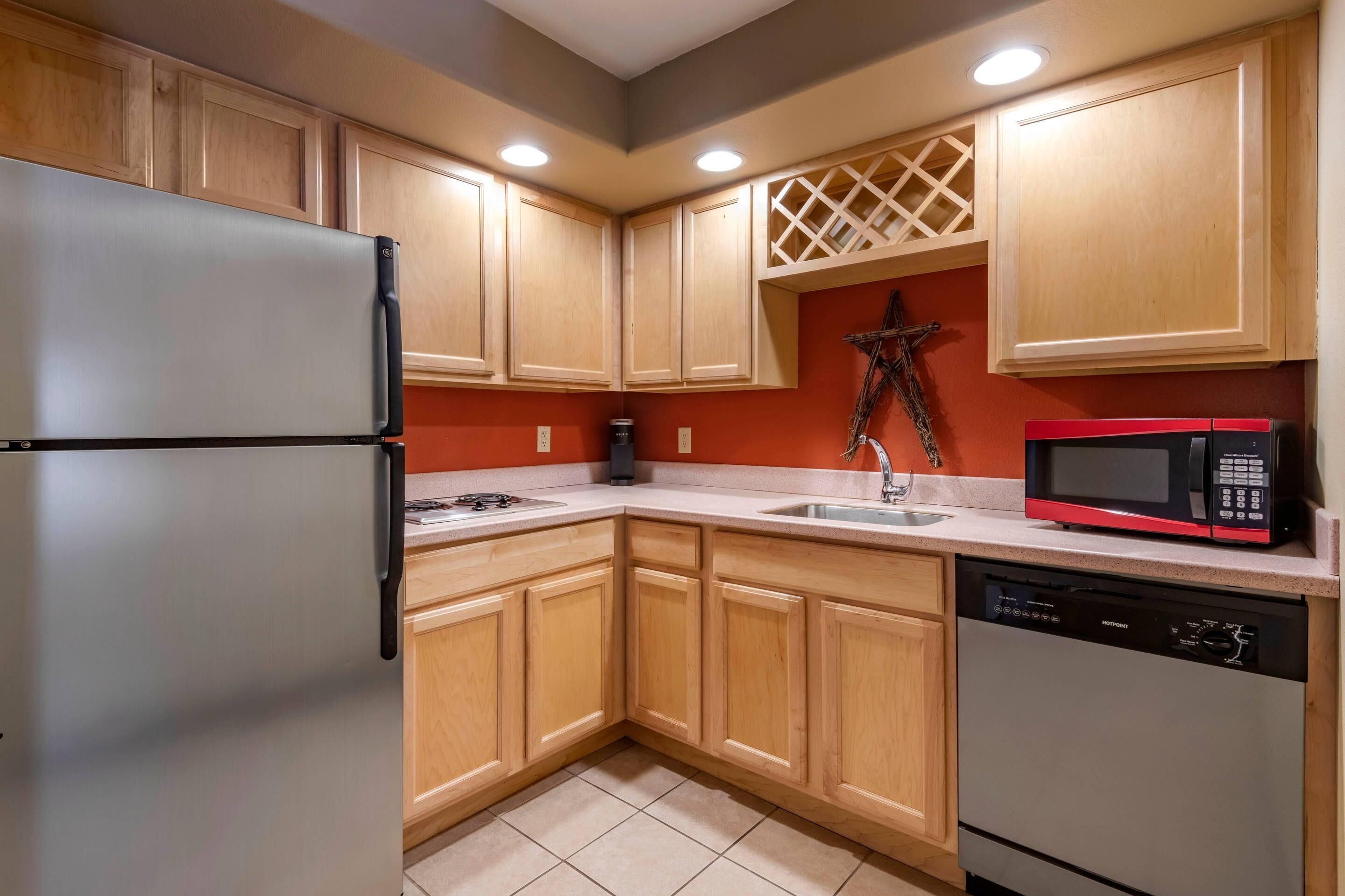 Una cocina con armarios de madera, un refrigerador de acero inoxidable, un microondas y un lavavajillas.