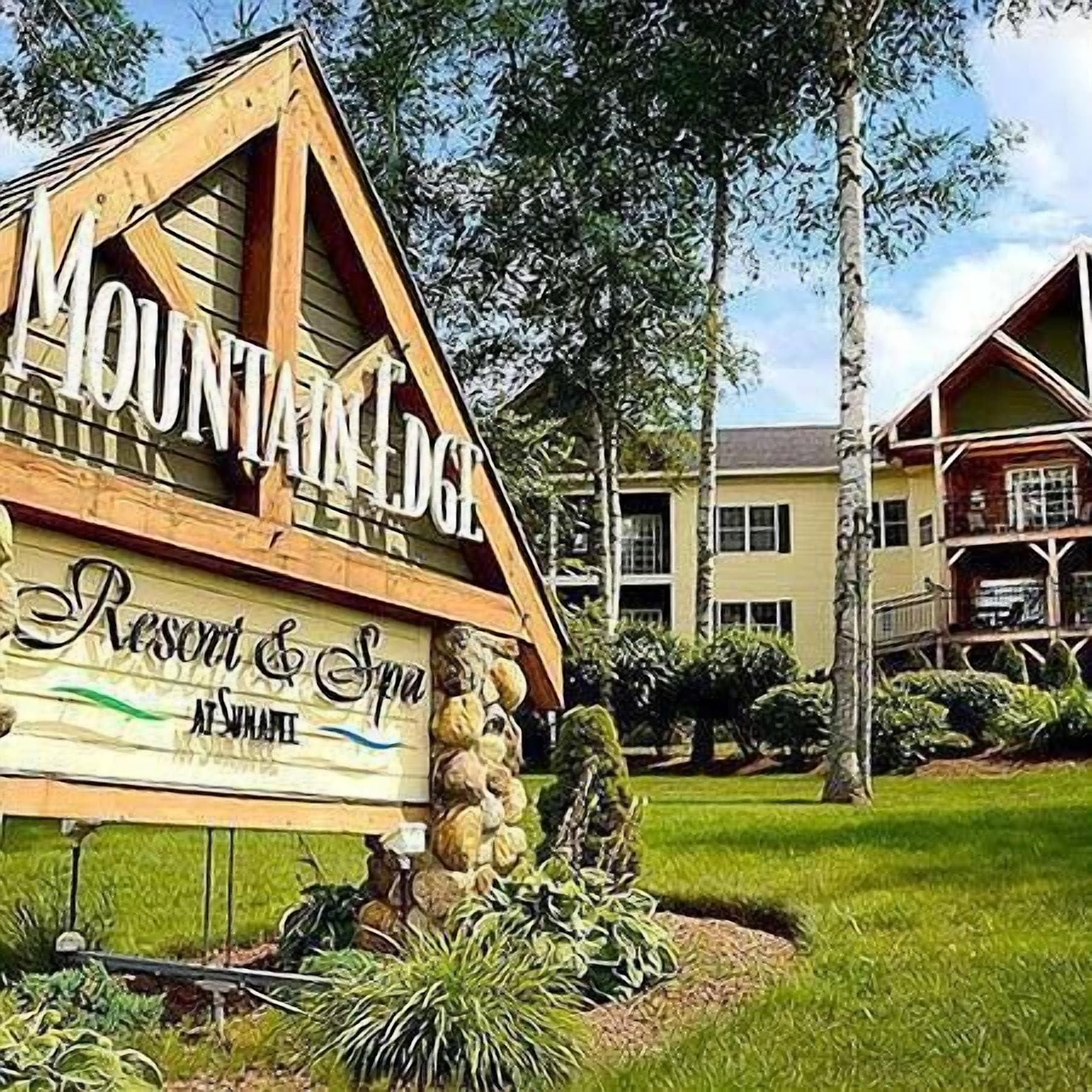Une enseigne en bois indiquant « Mountain Lodge Resort & Spa », avec un pilier en pierre et un jardin aménagé.