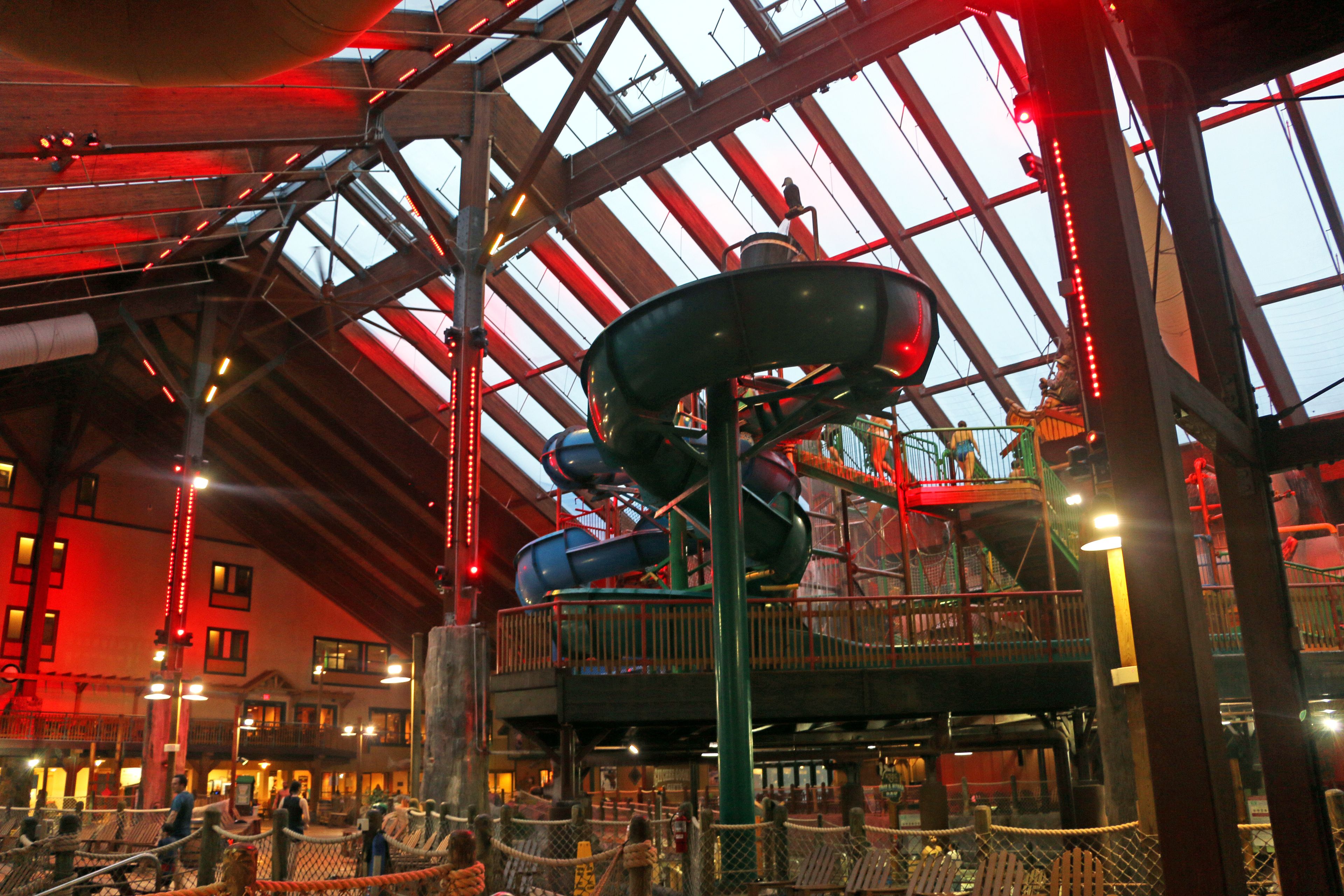 A large indoor amusement park with a water slide and a rope bridge.