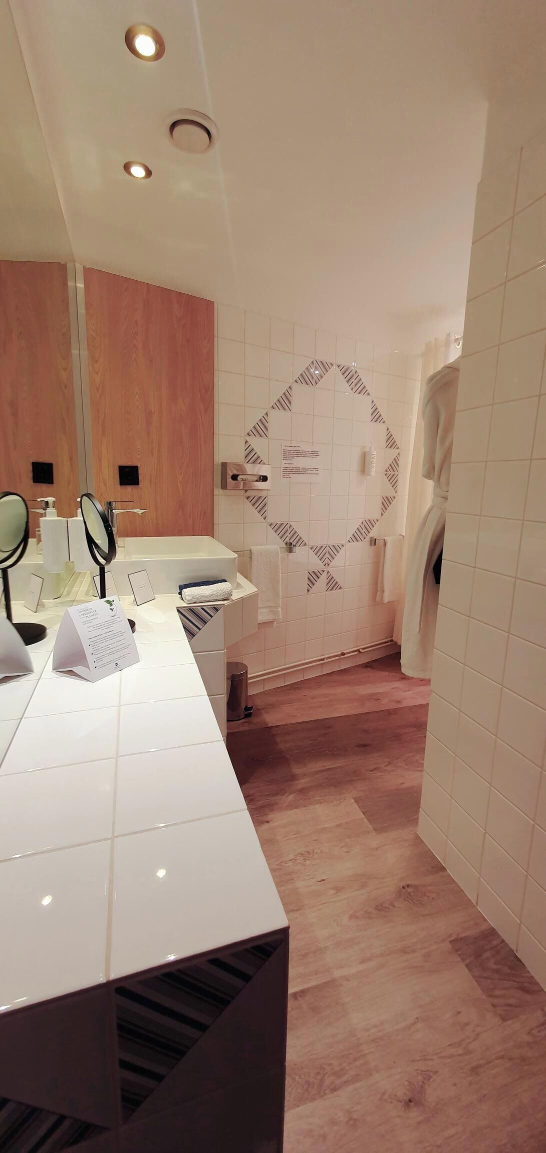 A modern bathroom with a vanity, mirror, and a shower area.