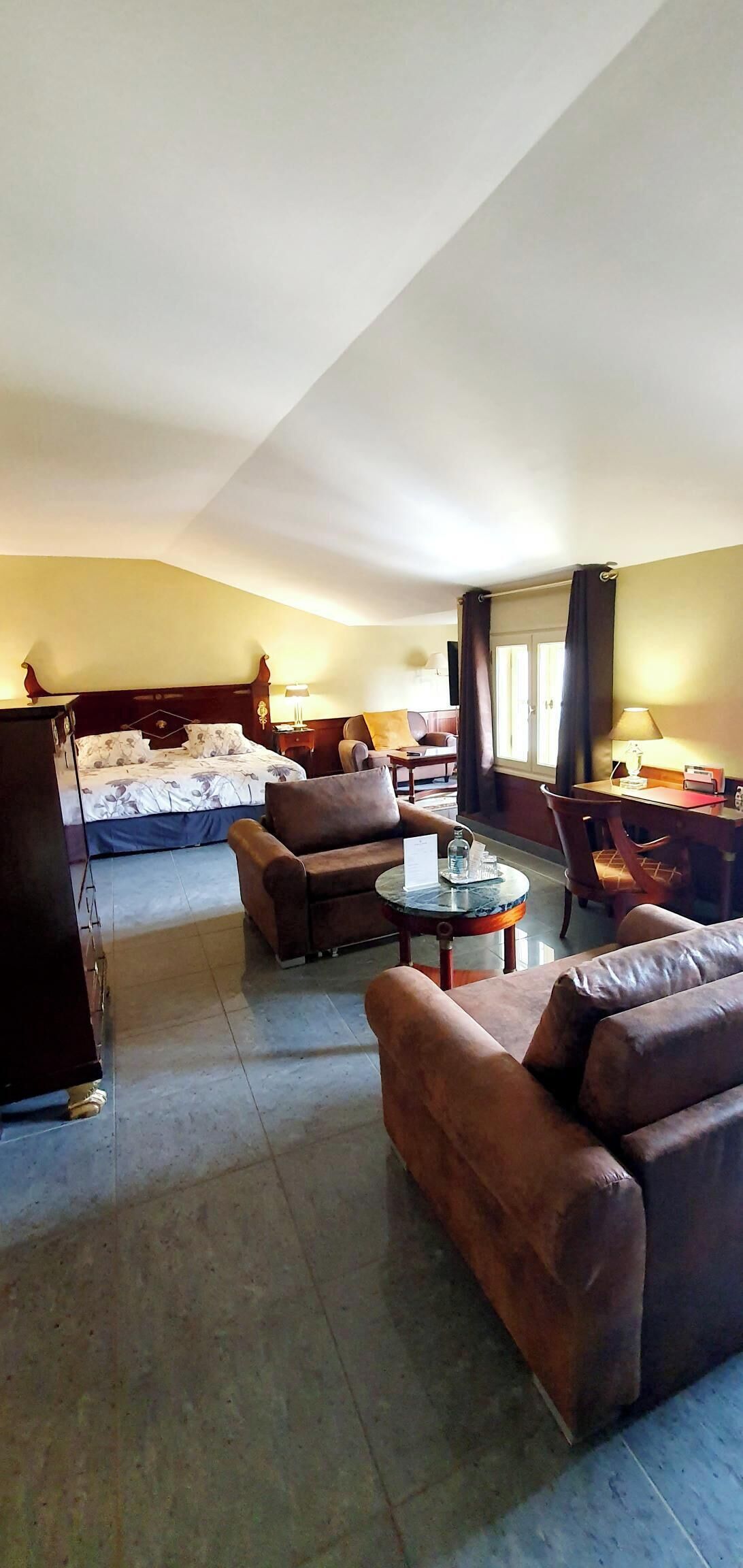 A hotel room with a bed, two sofas, a coffee table, and a TV.