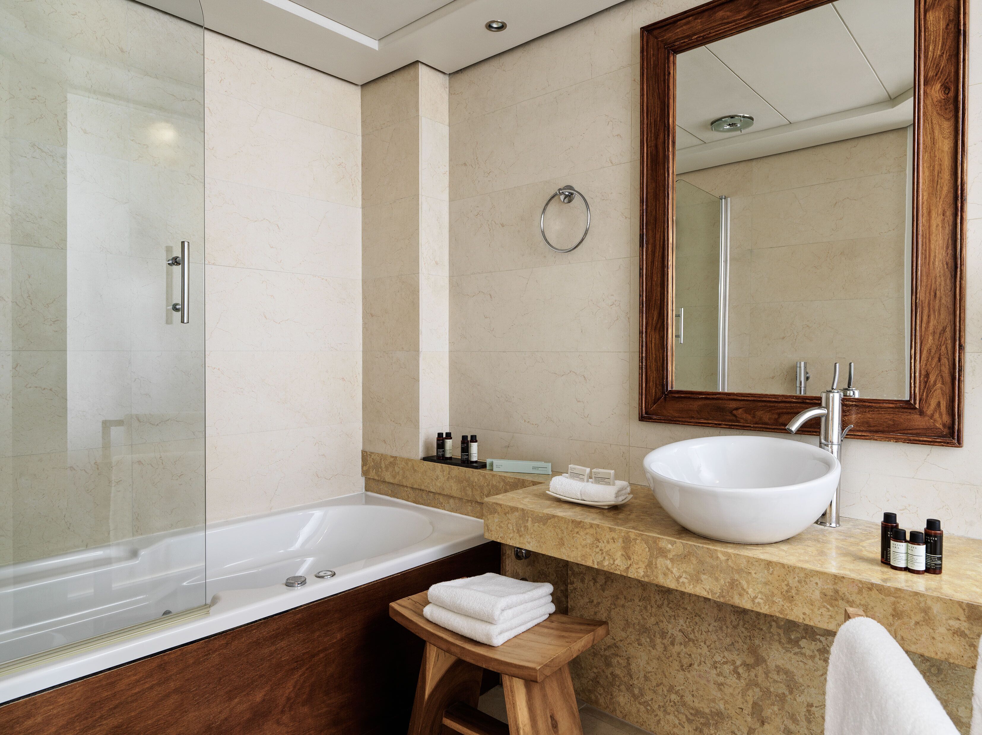 A modern bathroom with a glass-enclosed shower, a large white sink, and a wooden vanity.