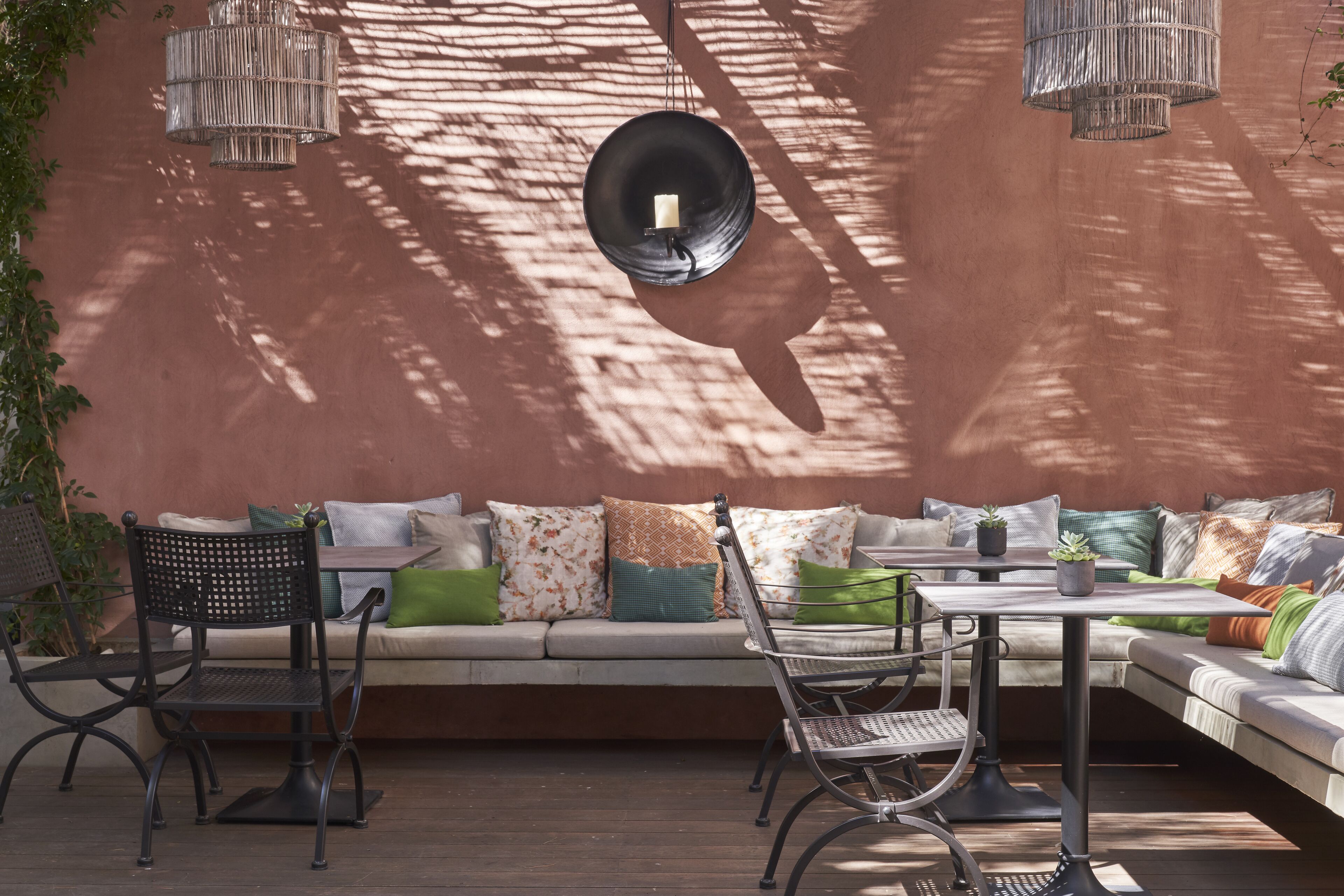 An outdoor seating area with a sofa, chairs, and a table, featuring a wall-mounted light fixture and a candle.