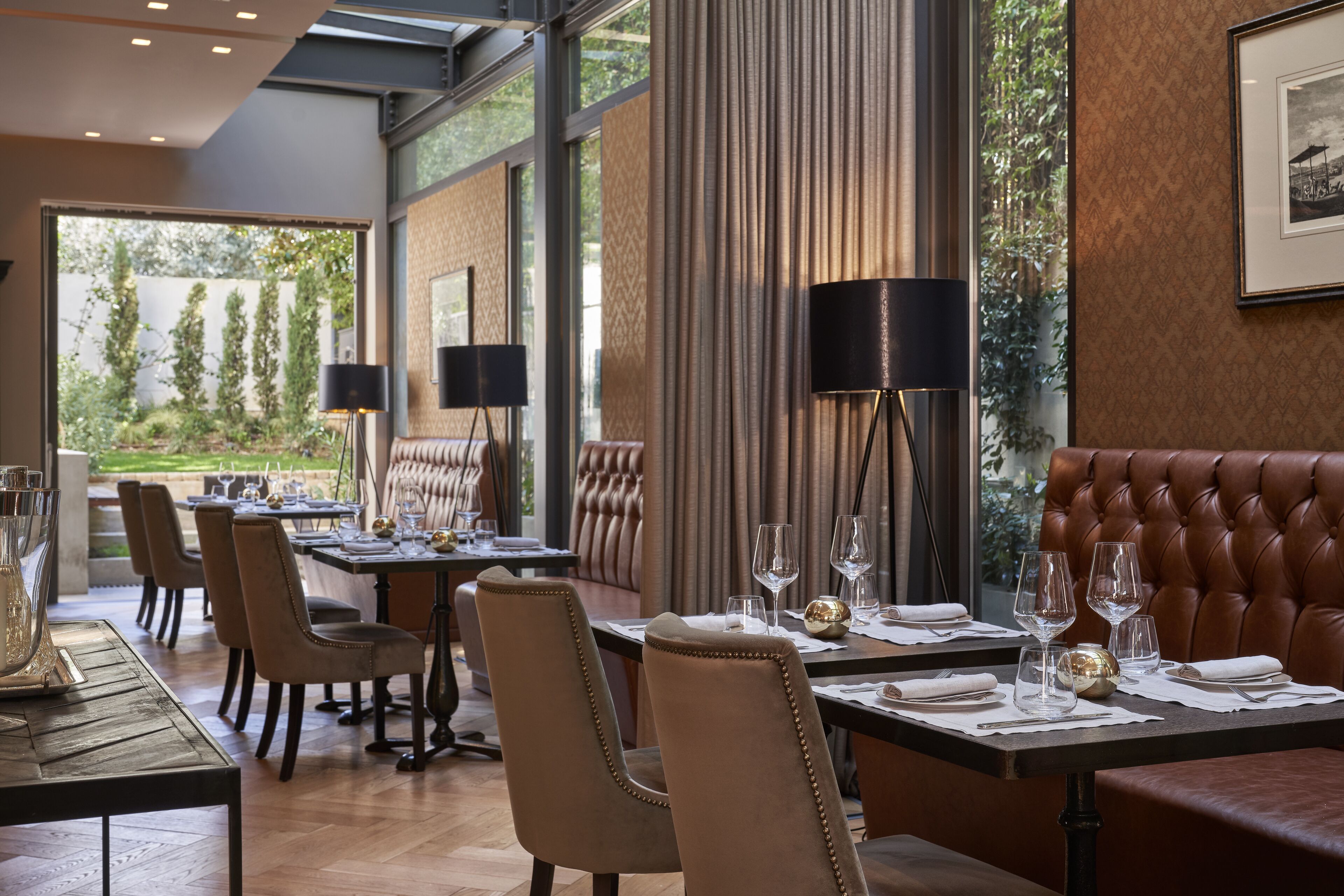 Un restaurant doté de plusieurs tables, de chaises et d’une grande fenêtre donnant sur un paysage verdoyant.
