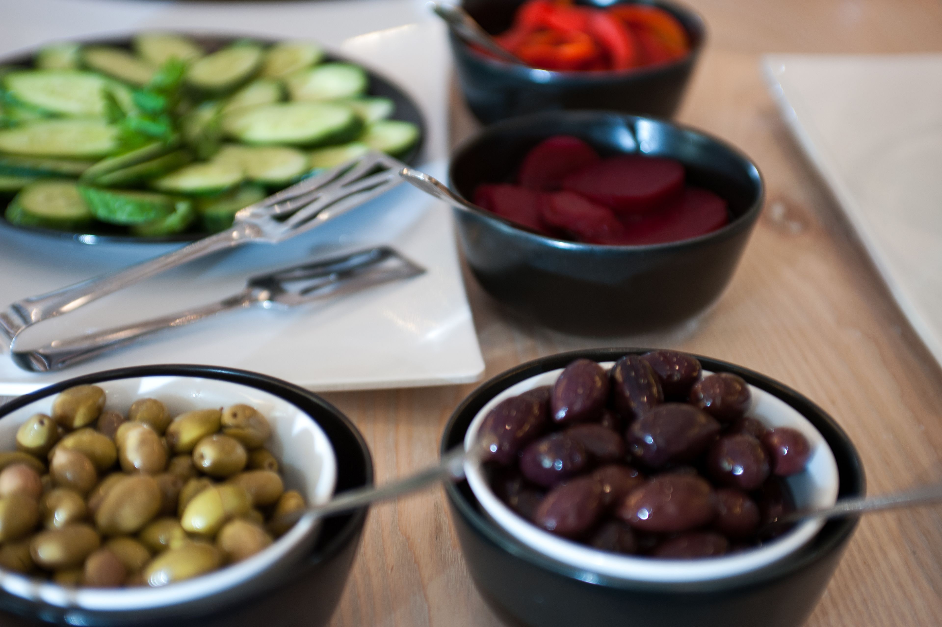 Ett bord med olika sorters mat, inklusive oliver, gurkor och rödbetor.