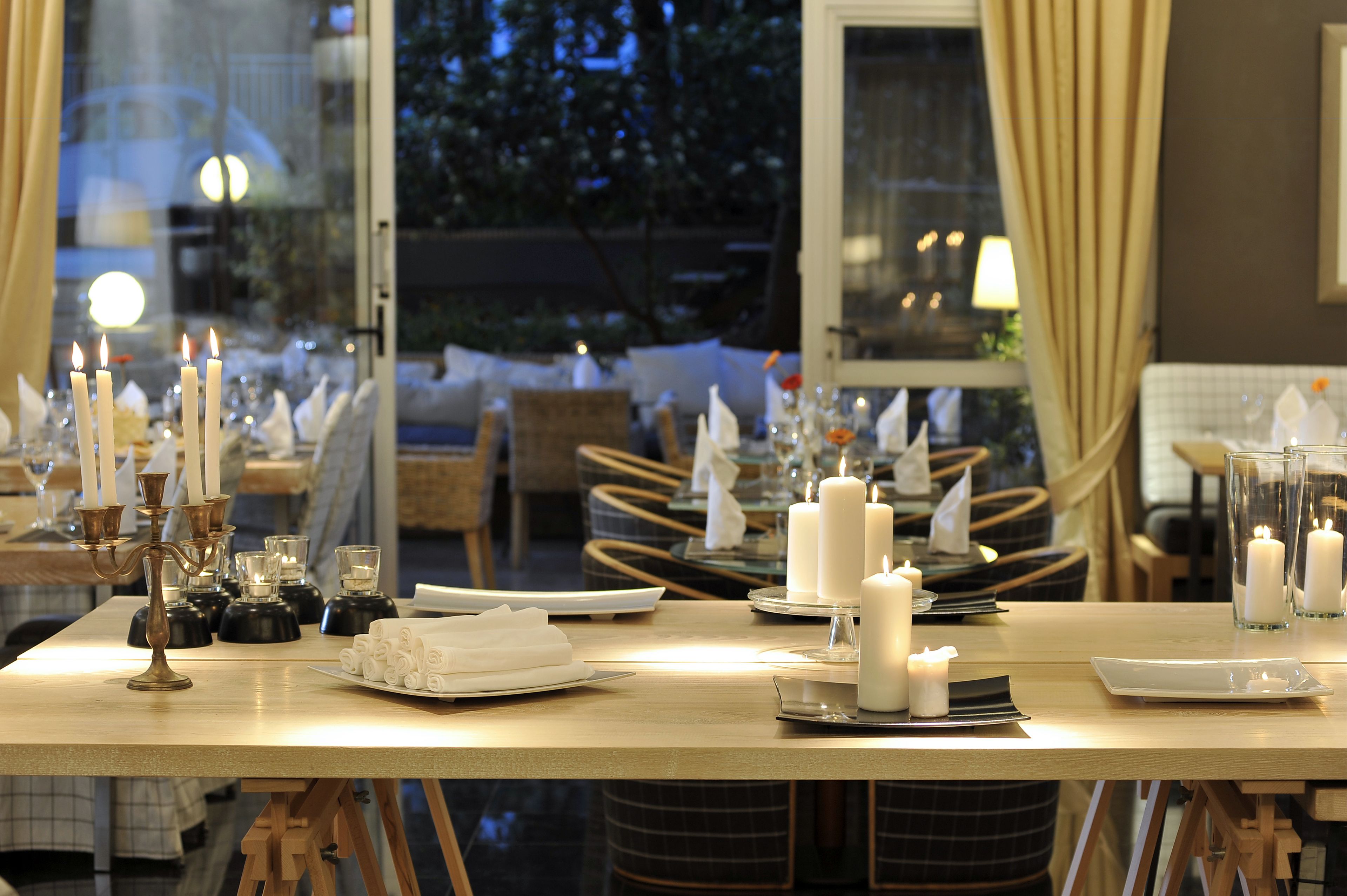 A dining table set for a meal with candles, plates, and cutlery.