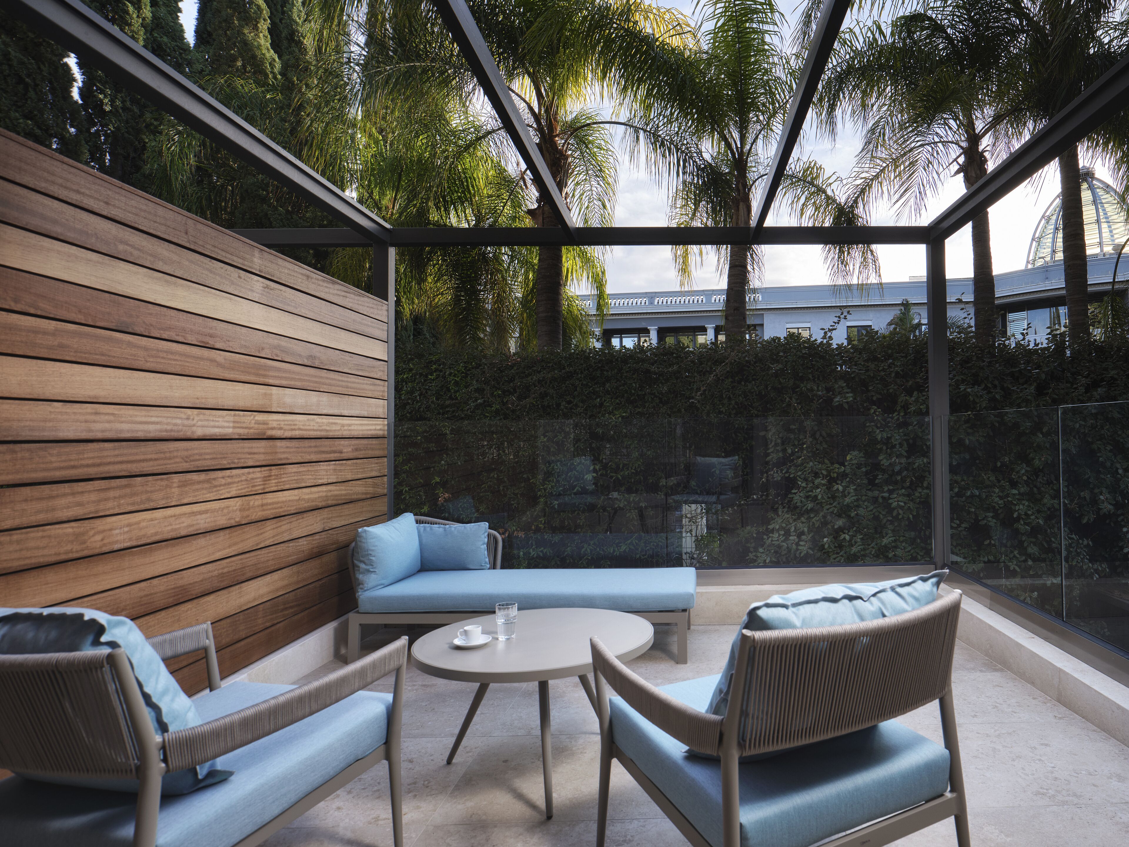 A modern outdoor seating area with a wooden wall, wicker chairs, and a round table.
