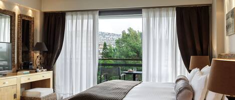 A hotel room with a bed, a desk, a chair, a television, and a balcony with a view of the city.
