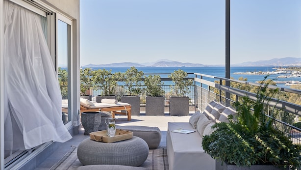 Varanda com vista para o mar, um sofá, uma mesa e uma janela com cortinas.