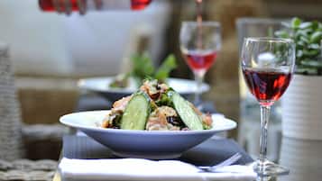 Un tavolo con un'insalata, un bicchiere di vino rosso e una bottiglia che viene versata.