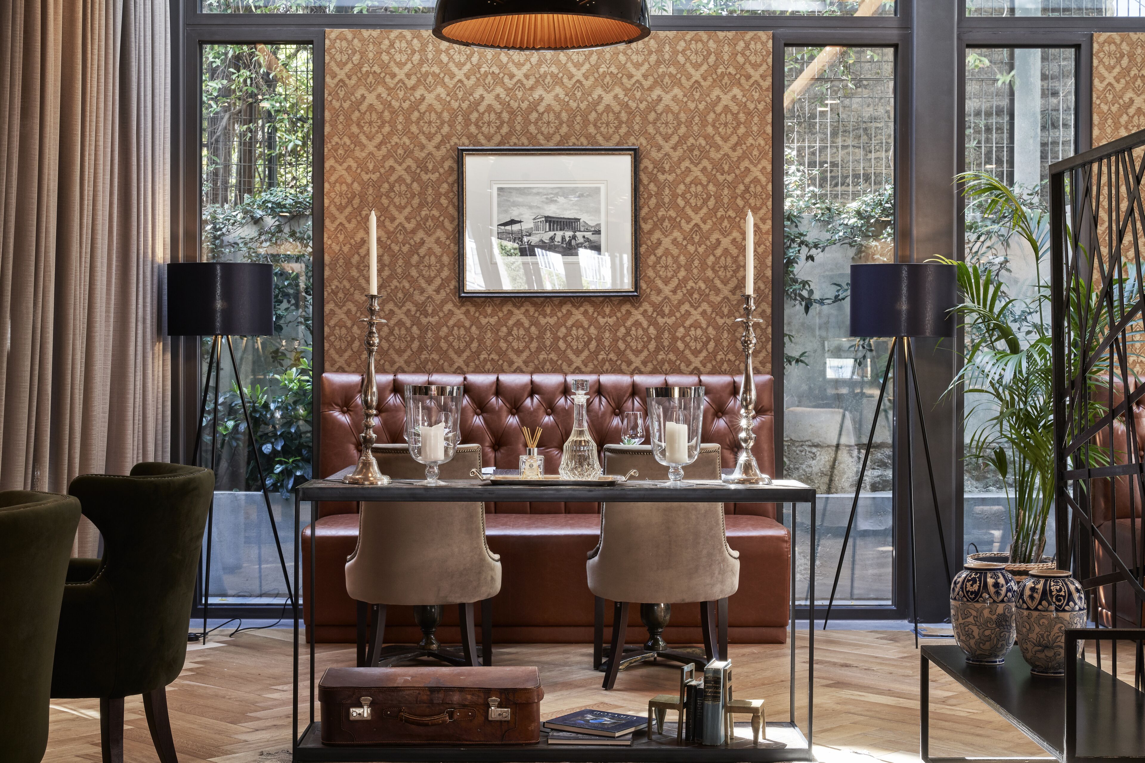 A dining area with a table set for four, a leather bench, and a large window with a view of greenery.